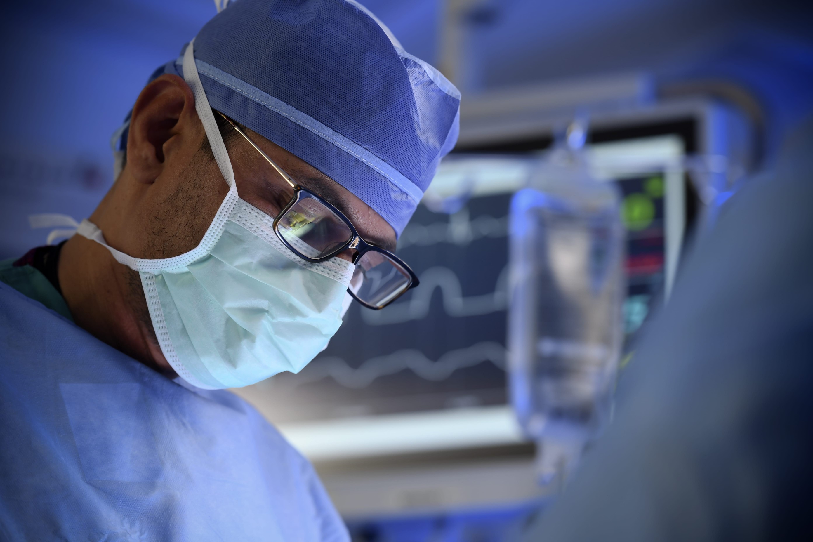 A surgical oncologist in operating attire performs a clinical trial procedure to treat a brain tumor