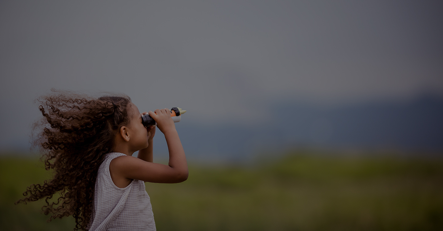 Young girl with binoculars looking out into a field