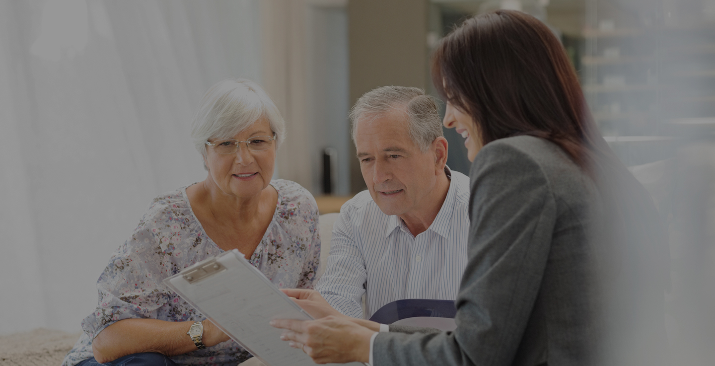 An elderly couple discuss financial assistance for cancer care with a financial planning specialist