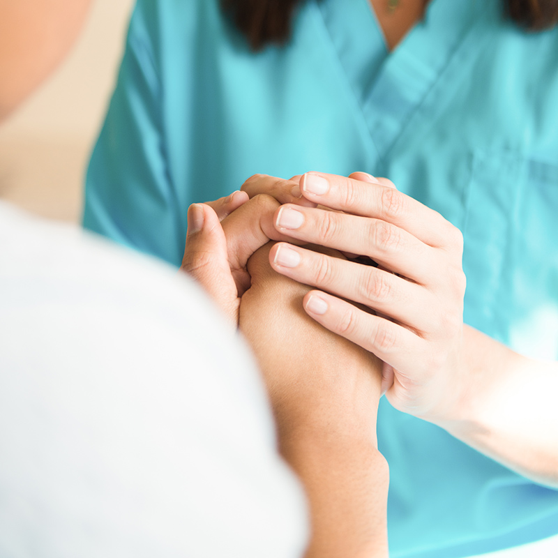A patient holding a nurse's hand for support