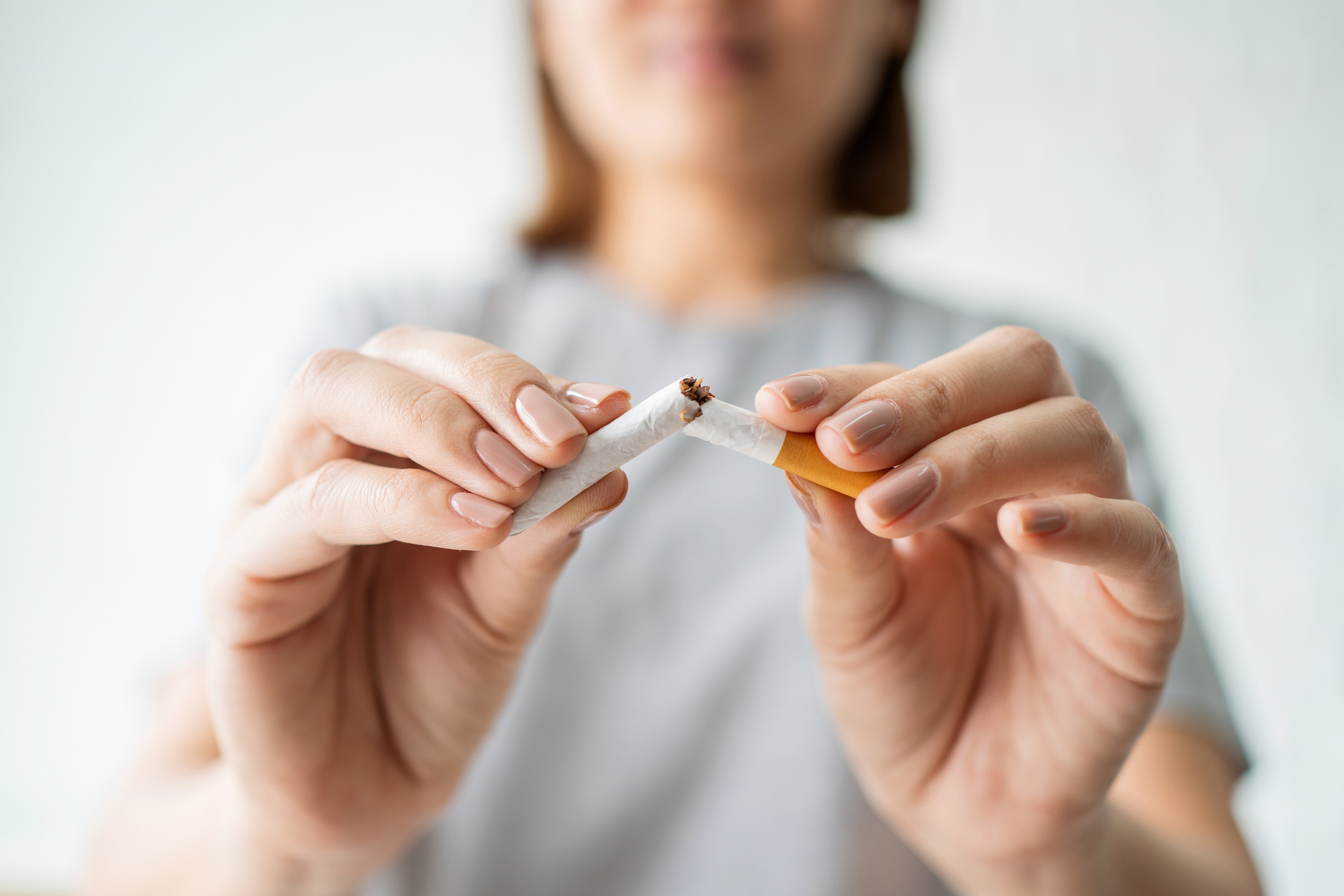 A woman breaks a cigarette in half.