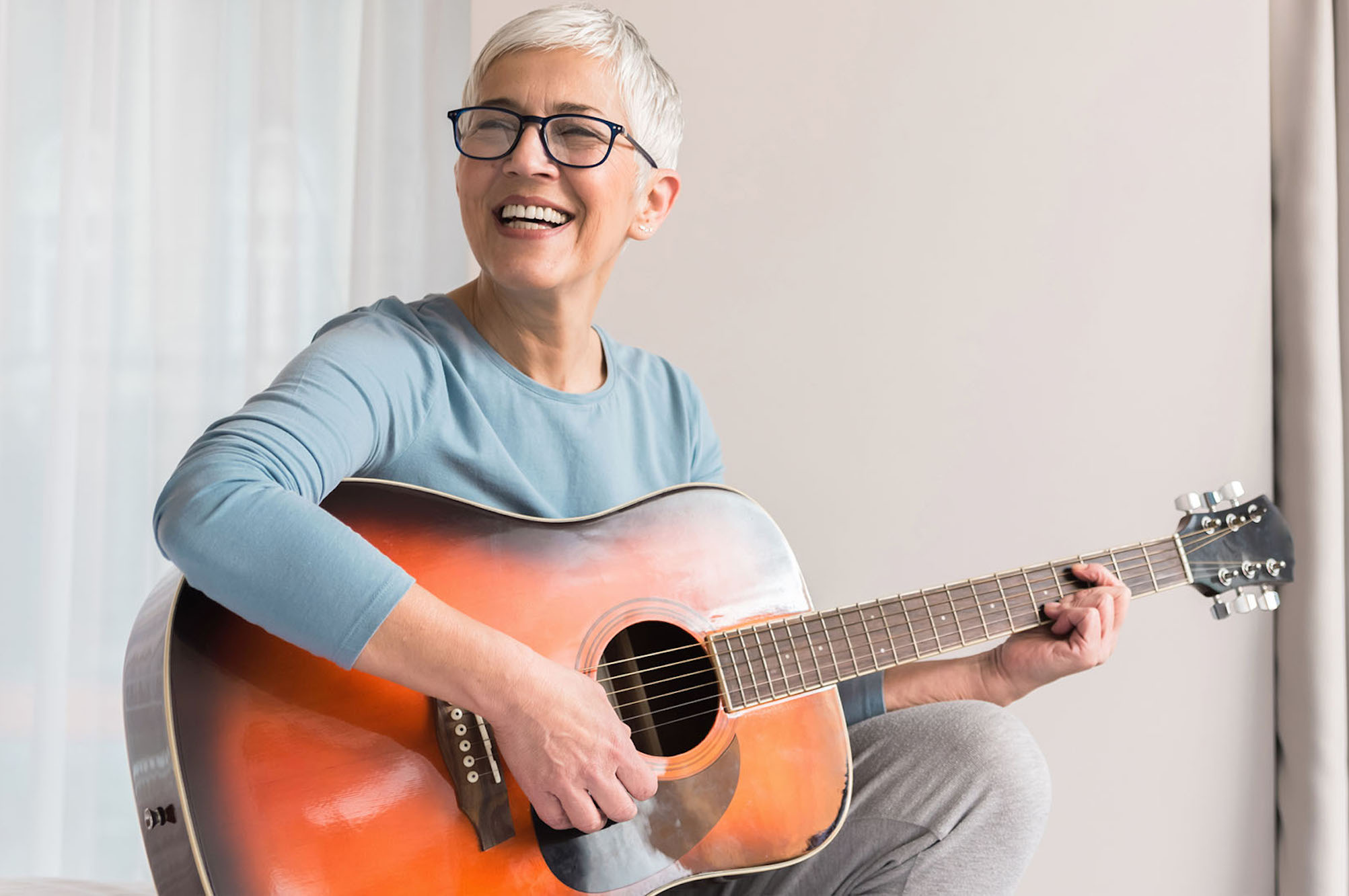 A Senior Lady Playing an Acoustic Guitar